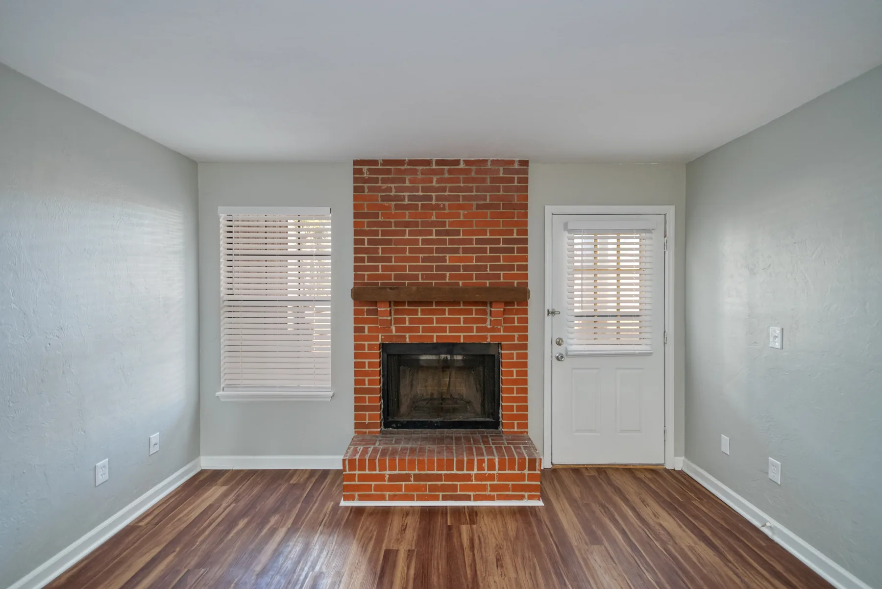 Brick wood-burning fireplace with hearth in a Castle Apartments living room
